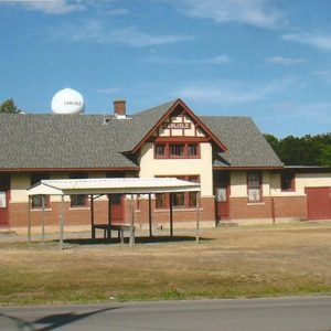 building with pointed roof and small pavilion in front with round water tower in background