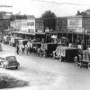 Trucks parked along busy street with men standing around them and cars passing by