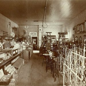 Interior of general store with white man and woman and items in display cases