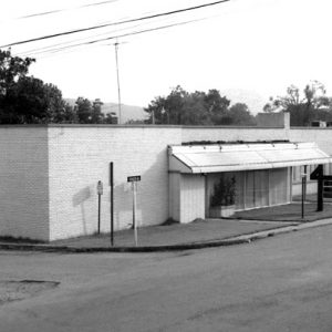 Nondescript single-story brick building on street corner with front windows "Carroll County Courthouse" post sign