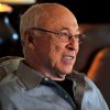 Old white man with glasses sitting in chair