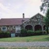 House with stone walls and three front arches with trees in front yard