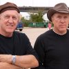 Two older twin white men wearing hats in matching black shirts