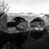 Stone arch bridge with concrete platform over creek