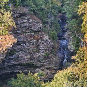 elevated distant view of waterfall and striated rock face, trees