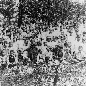 Group of white children and teachers with trees in the background