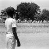 African-American boy watching white protesters marching in distance