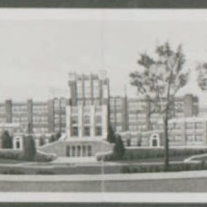 Multistory brick school building with two wings and trees in front yard