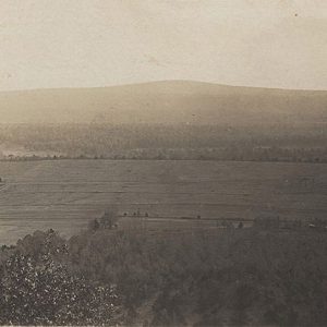 Elevated view of flat plain with some trees and hills in the distance