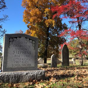 "Lottie" Charlotte Andrews Stephens gravestone in cemetery with other gravestones in the background under autumn trees