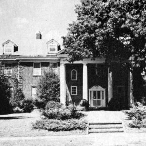 Three-story brick building with four columns and grounds