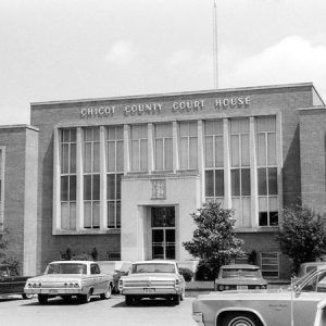 Multiple-story building with "Chicot County Court House" above the entrance and cars in the parking lot