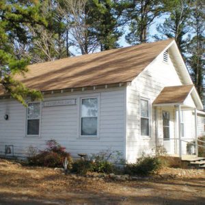 Single-story clapboard church with trees