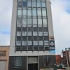 Tall multistory building with "For Sale" sign on its side on street corner