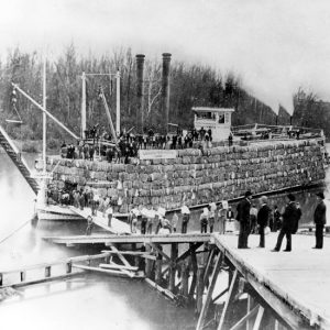 Passengers boarding a steamboat loaded with cotton bales