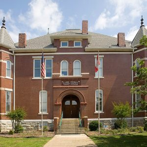 Multistory brick building with arched entrance way and steps on grass