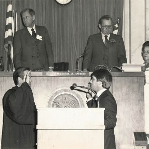 Four white men in suits and white woman in court room