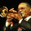 African-American man in suit with glasses playing a trumpet