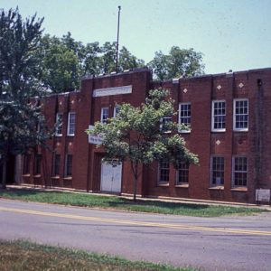 Two-story brick building with rectangular windows and square panes on street