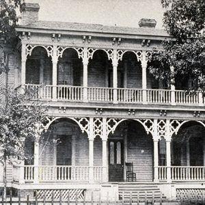 Multistory house with covered porch and balcony inside fence