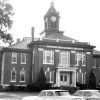 Multiple-story building with "Cleveland County Court House" written above the entrance and below its clock tower