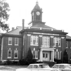 Multiple-story building with "Cleveland County Court House" written above the entrance and below its clock tower