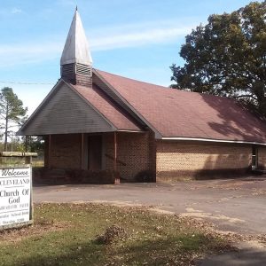 Brick church building with steeple and sign on parking lot