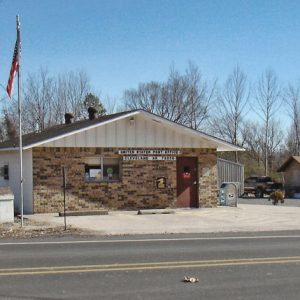 Brick building with flag pole and American flag as seen from across paved road