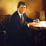 White man in suit and striped tie writing at his desk