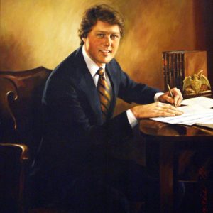 White man in suit and striped tie writing at his desk