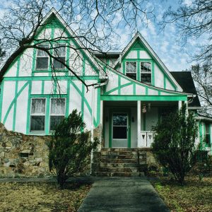 Green and white two-story house with stone steps and facade