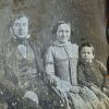 White man in suit with woman in dress and child in formal clothing