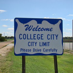 Blue and white "Welcome College City city limit" sign