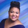 African-American woman smiling in purple dress with earrings