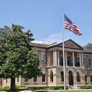 Flag pole in front of multistory building with covered porch and balcony