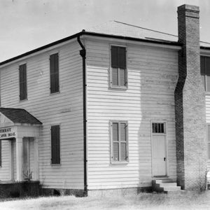 Two-story wooden building with brick chimney