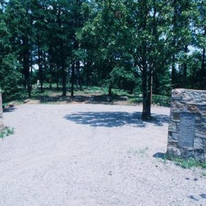 Stone columns with plaques on them in park with trees in the background