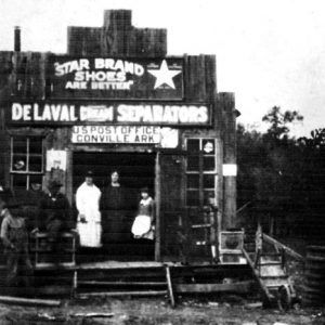 People standing outside post office on dirt road