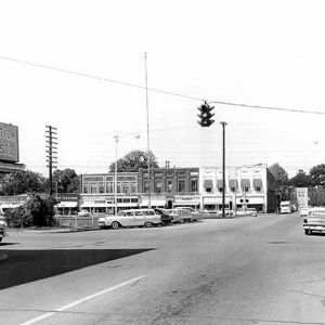 Cars on town streets with storefronts and traffic lights