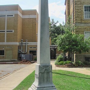 Obelisk monument with multistory buildings in the background