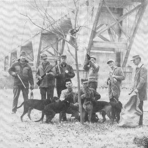 group of white men with hunting dogs beneath bridge