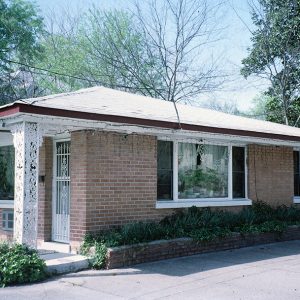 Single-story brick building with chair on covered porch