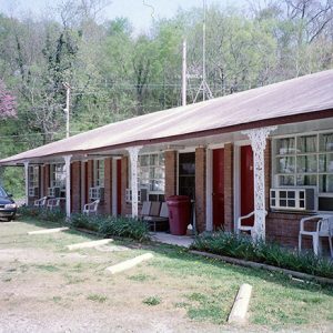 Single-story building with a series of red doors with car in parking lot