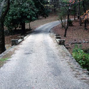 Paved road with small bridge amid forested area