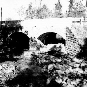 Side view of stone arch bridge over creek