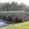 Stone arch spillway bridge with concrete platform on highway