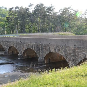 Stone arch spillway bridge with concrete platform on highway