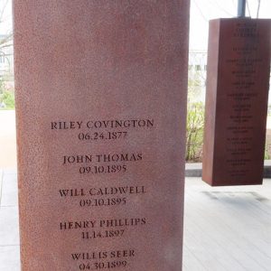 Rust-colored metal rectangle engraved with names and locations