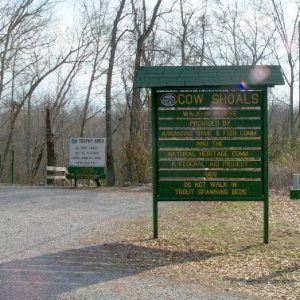 Road signs on gravel parking lot in wooded area