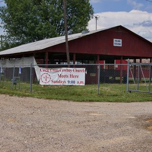 Red church pavilion and buildings behind a fence with red and white banner and gate